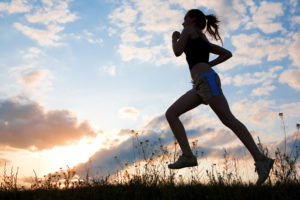 Silhouette woman run under blue sky with clouds and sun